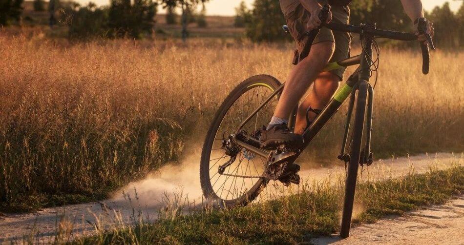 cyclist on gravel bike rides along dirt road