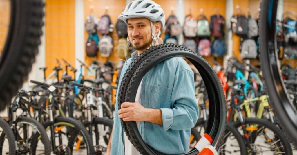 man holding bicycle tires in bike shop