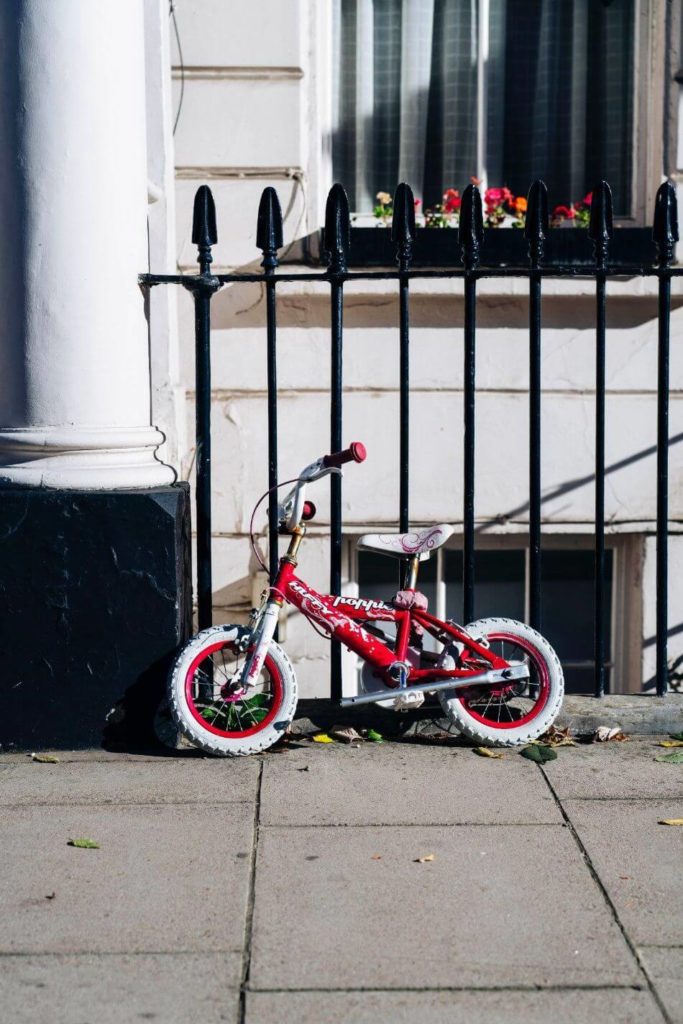 Childs bike on pavement sitting up against railings