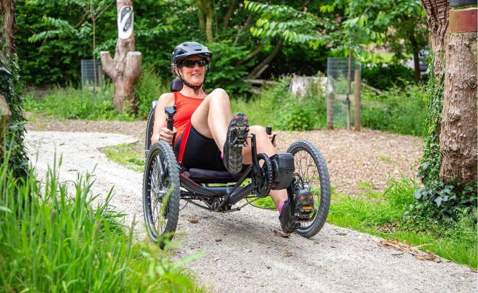 ICE Trail electric recumbent adult tricycle woman riding along gravel path 1