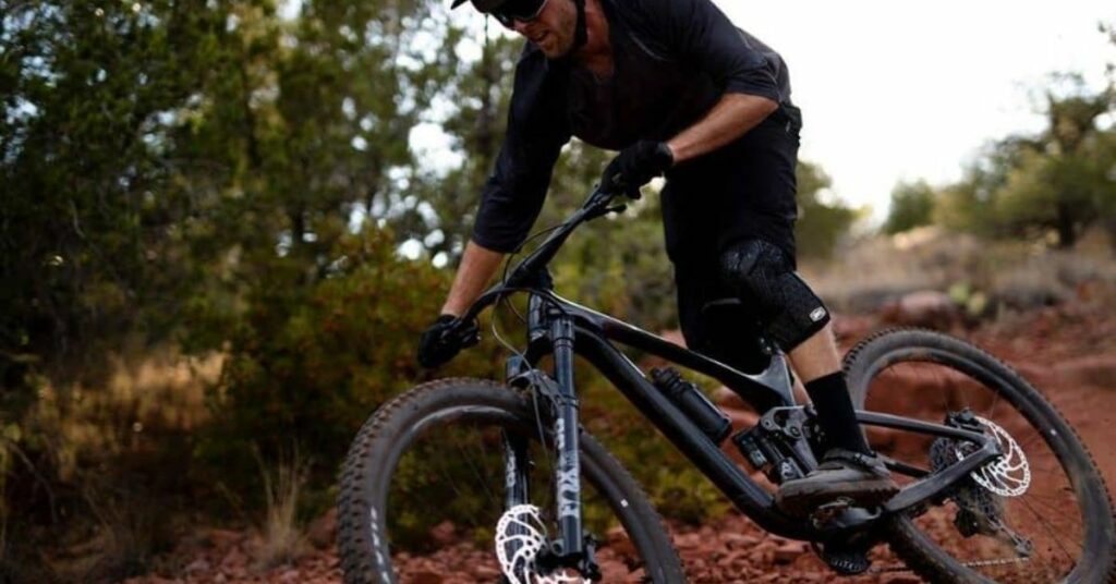 Man in black riding Giant mountain bike on red clay 1