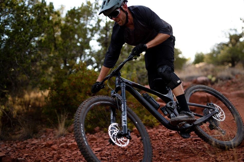Man in black riding Giant mountain bike on red clay