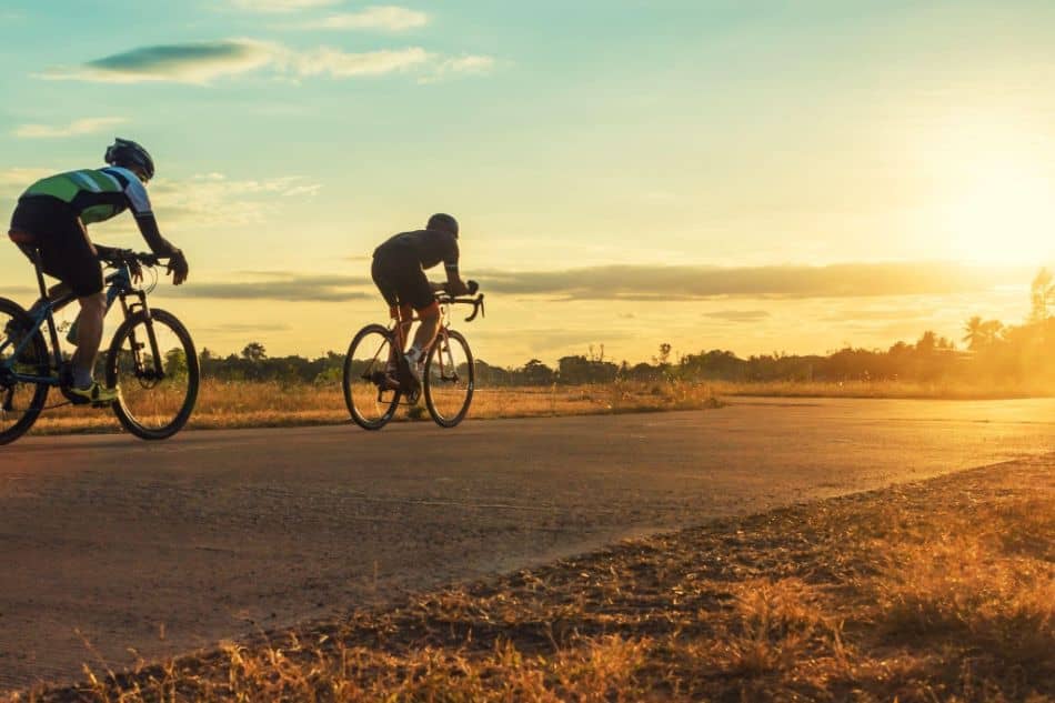 Silhouette group of men riding bicycle at sunset