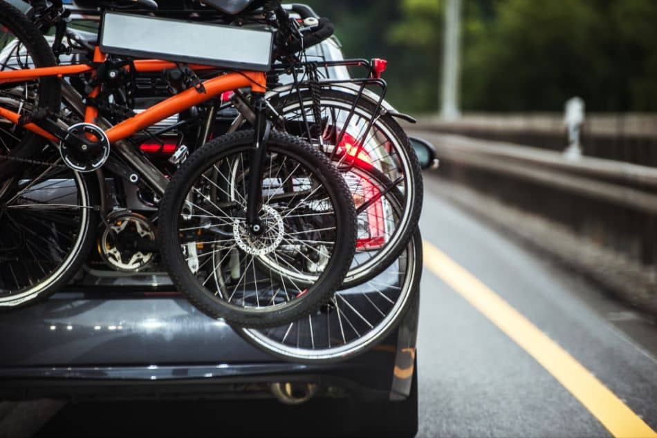 car driving on highway with three bikes loaded on trunk rack