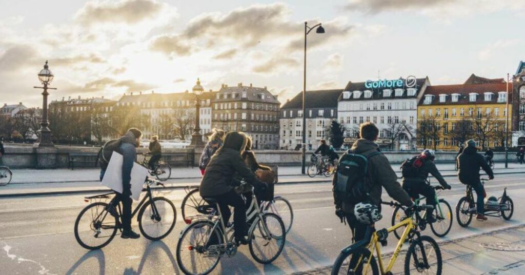 cyclists riding in Copenhagen Denmark with cloudy sunset sky