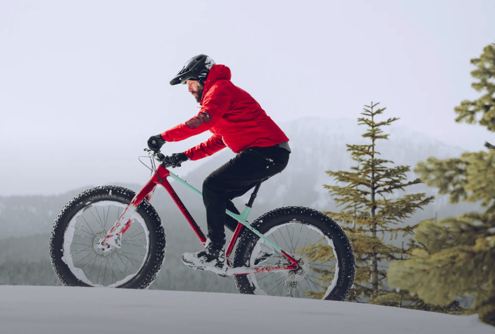 man in red jacket riding Rocky Mountain fat tire mountain bike in snow