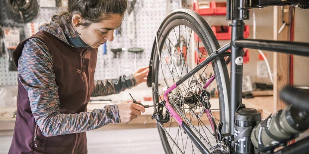 woman adjusting the rear derailleur on a bicycle in a bike shop