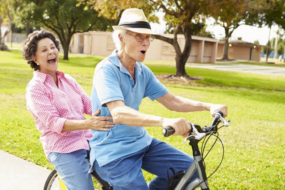 Man and woman riding a hybrid bike together next to a patch of grass1