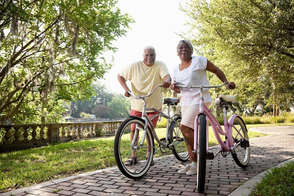 Man and woman seniors walking cruiser bicycles on the brick path7