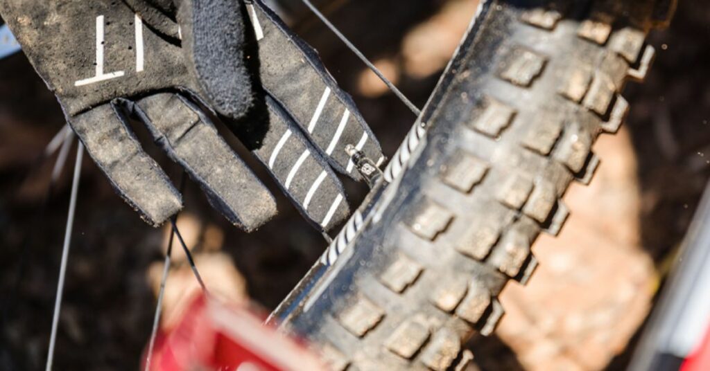 Mountain biker with gloves releasing pressure on mountain bike tire 1 1