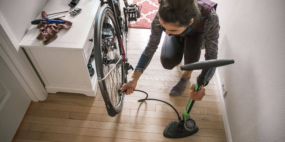 Woman pumping up bike inside house with green floor pump4