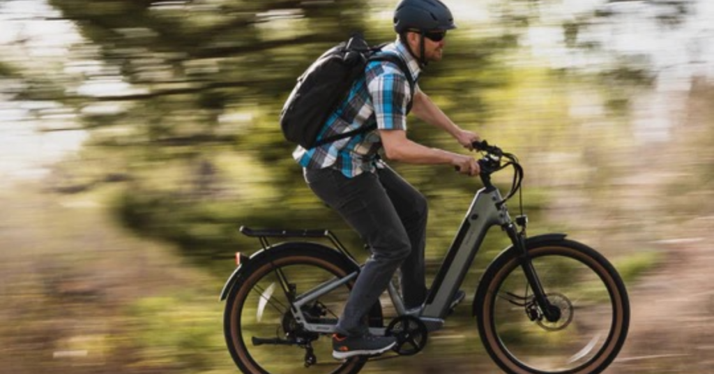 Man with backpack riding Velotric Discover 1 electric bike 1 1